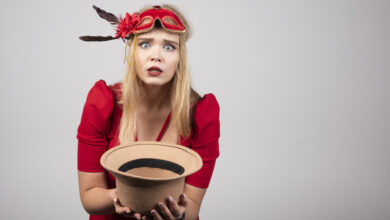 Young beautiful woman in red dress offering her hat and feeling depressed. High quality photo