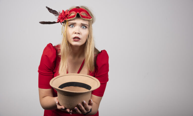 Young beautiful woman in red dress offering her hat and feeling depressed. High quality photo
